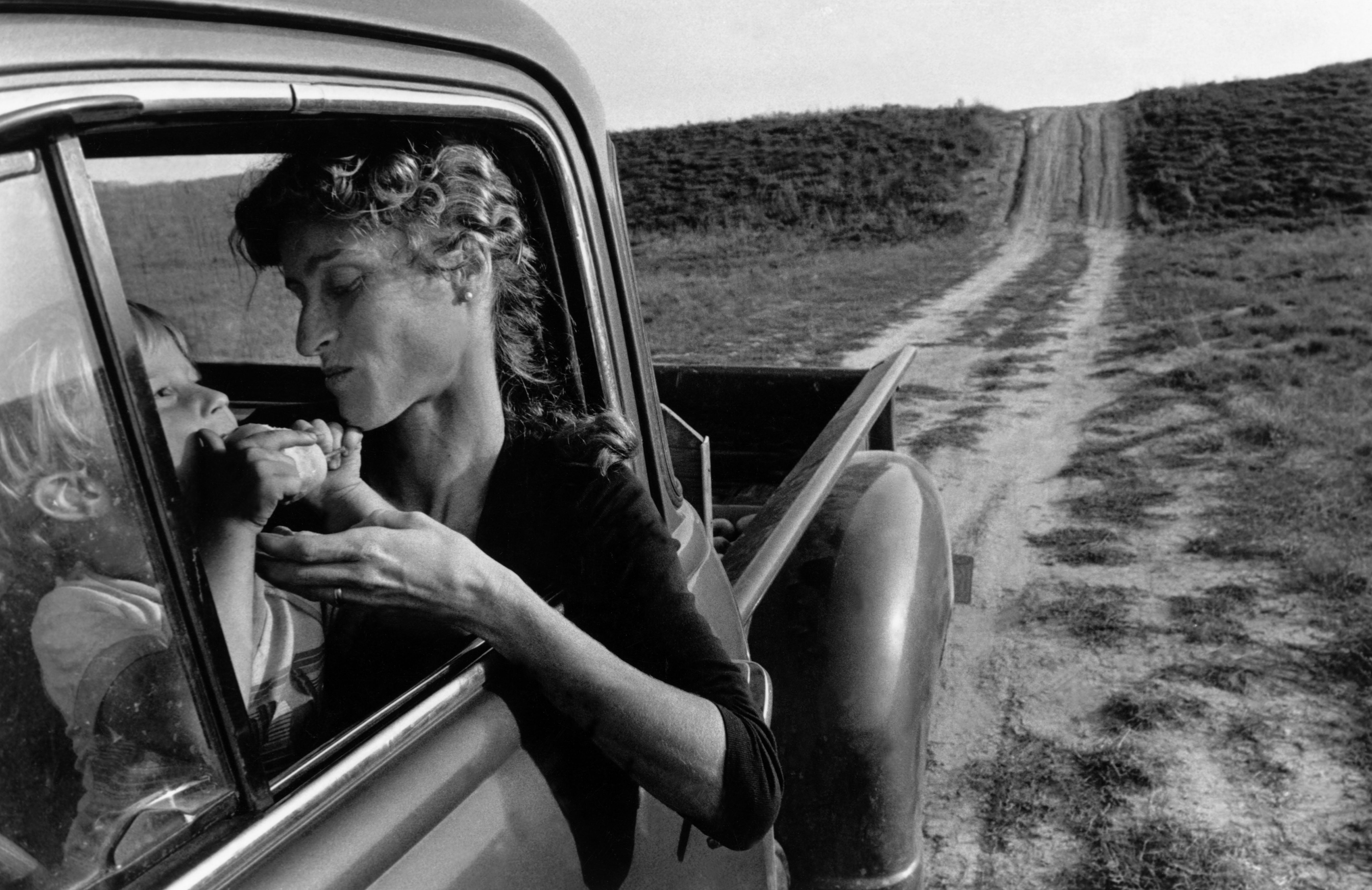 Fine Print: My oldest son Moses Towell eats a wild pear while Ann sits behind the wheel of a 1951 pickup truck. Lambton County, Ontario, Canada, 1983