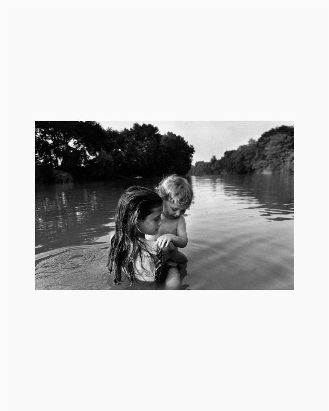 Fine Print: Two-year-old Isaac Towell is carried into the Sydenham River by his older sister Naomi to introduce him to water. Lambton County, Ontario, Canada, 1996